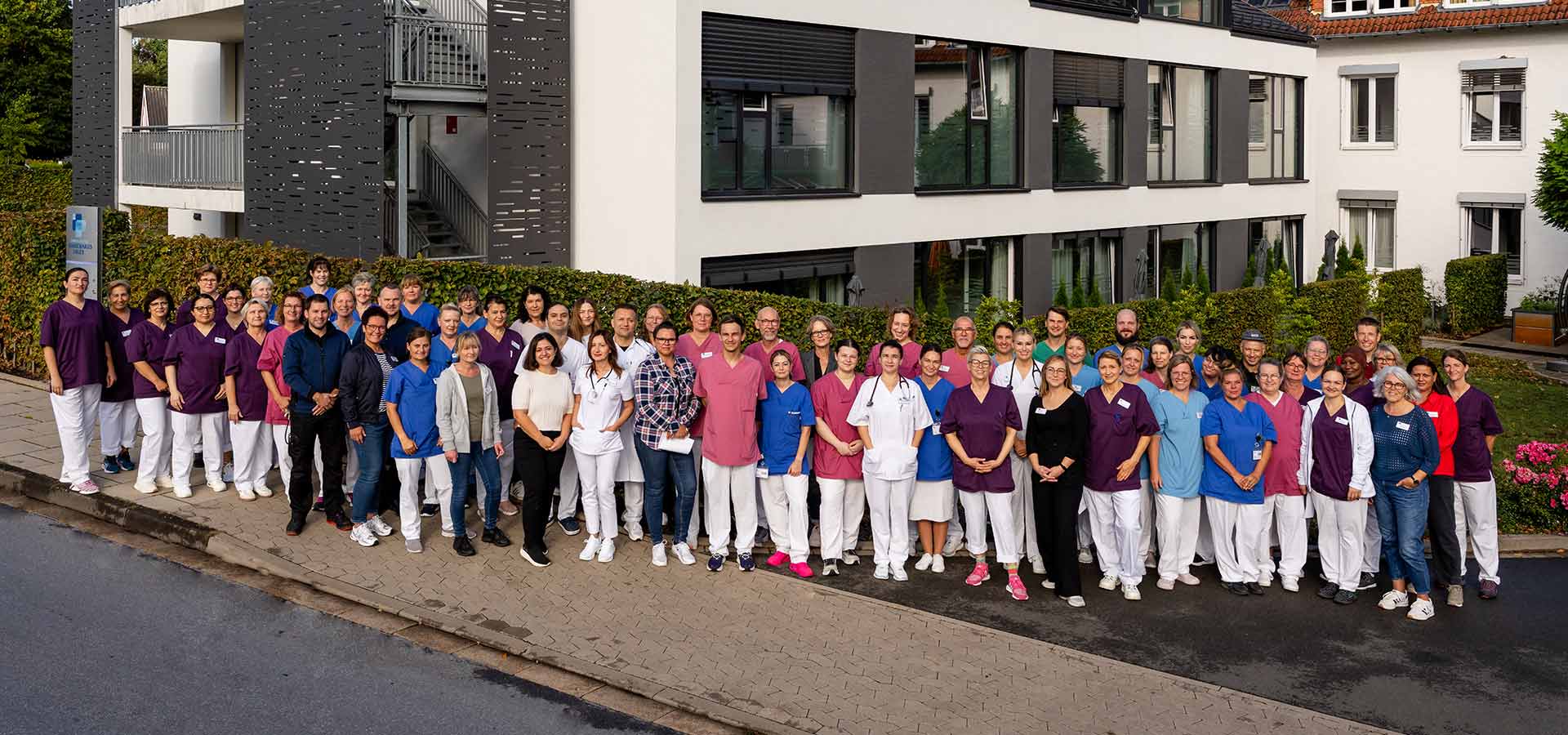 Team der Geriatrischen Fachklinik Enger, Außenaufnahme aller Mitarbeiter vor dem Krankenhausgebäude