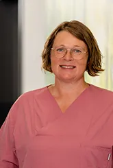 Porträt der Leiterin der Physiotherapie in altrosa Pflegeoberteil vor unscharfem Hintergrund