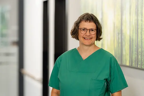 Porträt der Logopädin in grünem Pflegeoberteil vor unscharfem Hintergrund