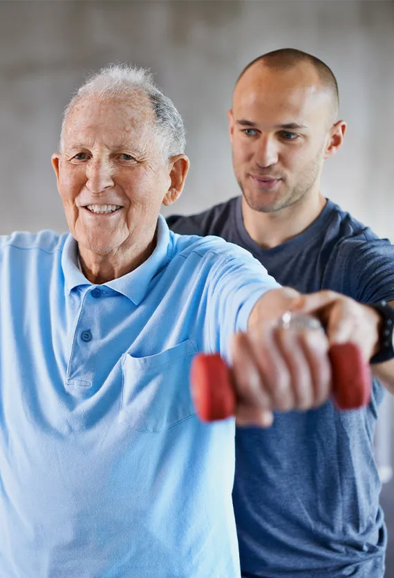 Ein Physiotherapeut, der einem älteren Mann beim Hanteltraining hilft