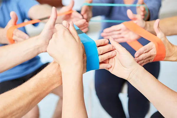 Ergotherapie, Trainer hilft bei Übung mit dem Elastikband